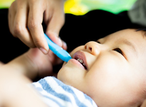 A baby is getting it's teeth cleaned with a toothbrush.