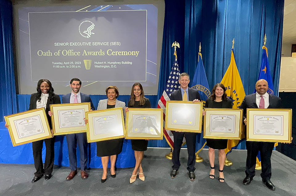 HRSA leaders stand for a portrait holding their Senior Executive Service Oath of Office Award certificates. 