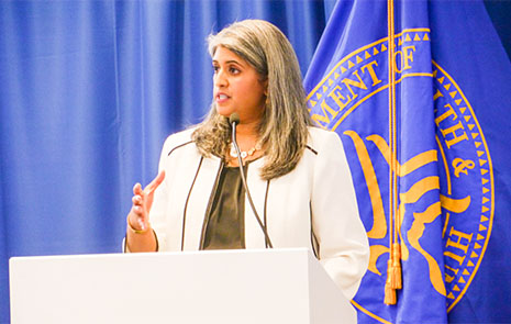 Health Systems Bureau Associate Administrator Suma Nair speaks on stage from a podium.