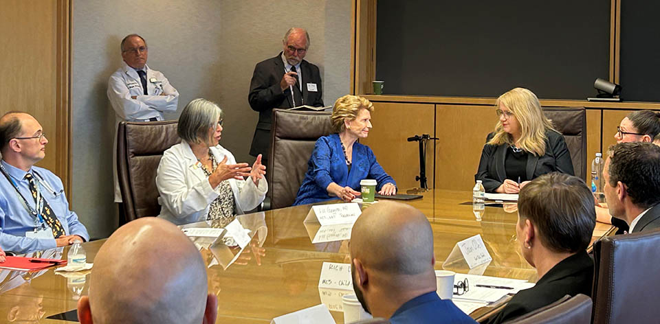 Participants including Carol Johnson and Senator Debbie Stabenow engage in discussion at  roundtable event.