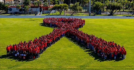 Group portrait of HRSA staff standing to form a red ribbon.