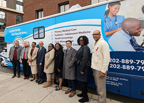 A group of individuals pose in front of a mobile healthcare van.
