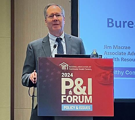 BPHC Associate Administrator Jim Macrae speaks from a podium at the 2024 P&I Forum