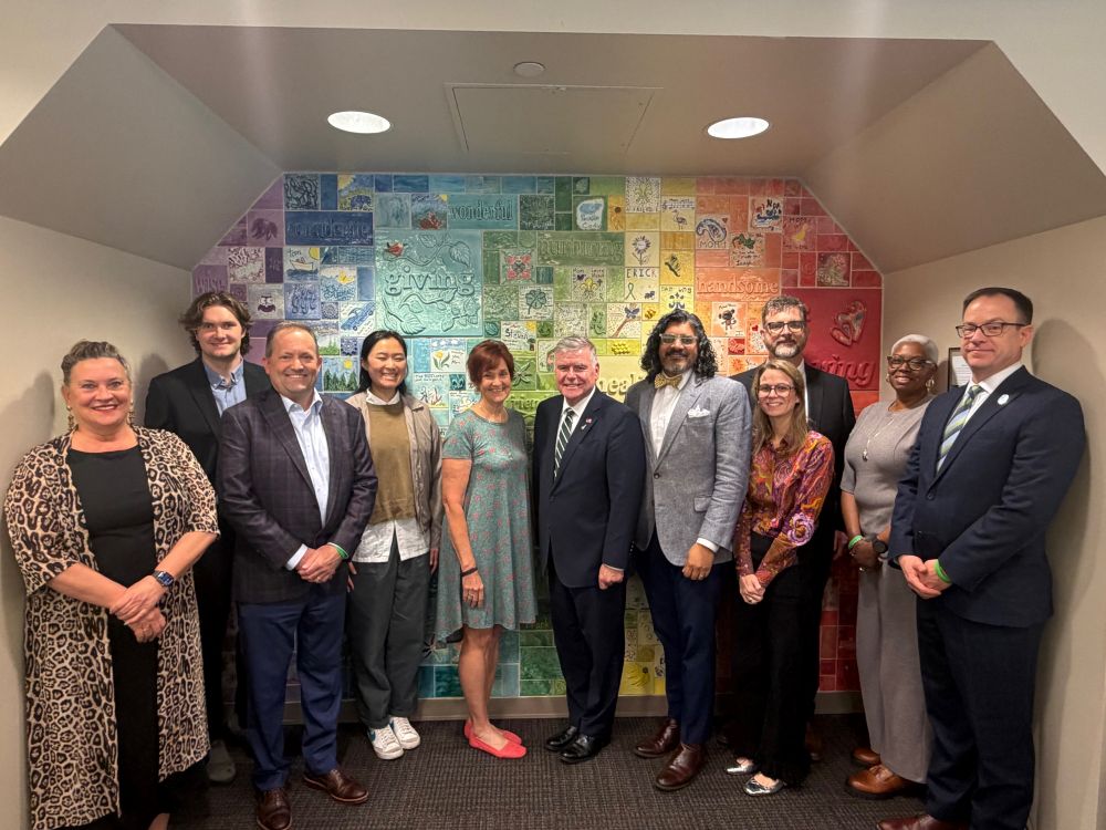 A group of people are standing in front of a colorful wall.