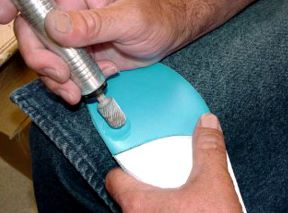 A Dremmel tool is being used on a custom-made orthotic.