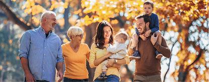 A group of four people are walking while two of them are holding children.