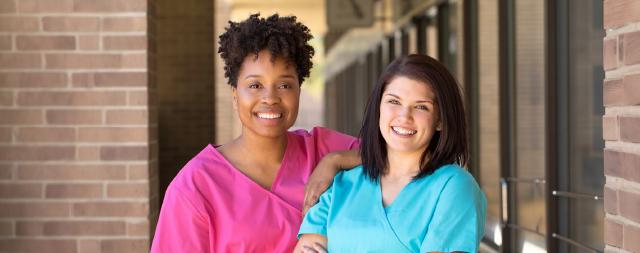 Two smiling nurses outside of an office 